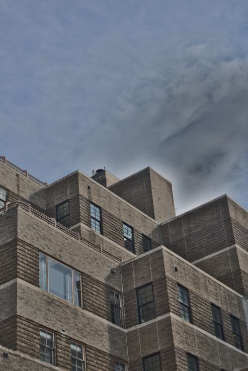 View of walls and roofline illustrating complex setbacks with grey cloud above
